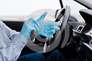 Man in a car putting on protective mask and gloves during pandemic coronacirus covid-19