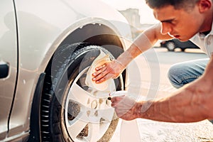 Man with car rims cleaner, carwash