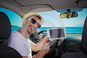 Man in car showing blank screen digital tablet device. Travel an