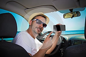 Man in car showing blank screen smartphone. Travel and technolog