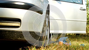 A man from a car throws out a bag of garbage on the grass, nature, close-up, pollution by nature`s garbage, garbage and