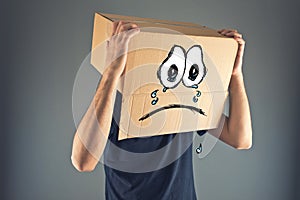 Man with cardboard box on his head and sad face expression