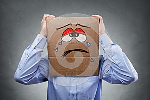 Man with cardboard box on his head showing sad expression