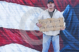 Man with cardboard sign, Stop Killing No More Guns, with American Flag,