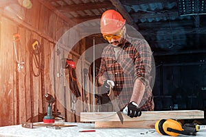 A man carpenter cuts a wooden beam using a handsaw, male hands with a saw closeup. Work with wood