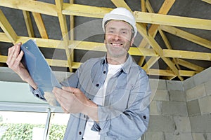 man carpenter holding clipboard at construction site