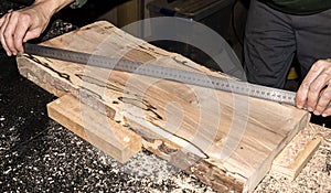 Man carpenter measuring wooden plank with ruler on carpentry table