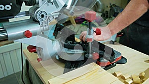 A man carpenter is working with wood using a special machine in a studio. The joiner uses a circular saw machine