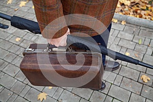 Man with carpetbag in jacket stands in alley of autumn park