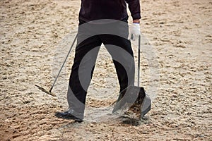 A man carries away horse manure removed from a racetrack