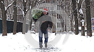 Man carries a Christmas tree packed in a grid just bought at the Christmas market