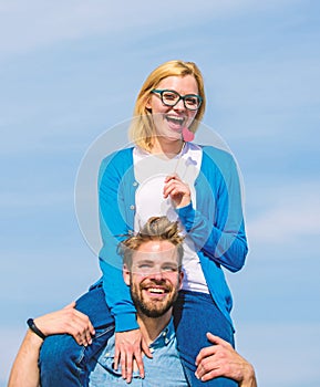 Man carries girlfriend on shoulders, sky background. Romantic date concept. Couple happy date having fun together