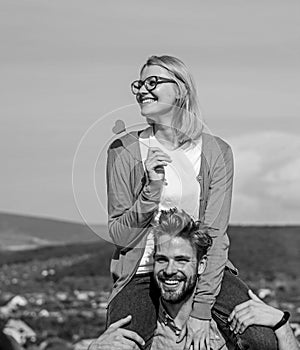 Man carries girlfriend on shoulders, sky background. Romantic date concept. Woman holds heart on stick symbol of love