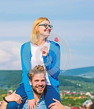 Man carries girlfriend on shoulders, sky background. Romantic date concept. Woman holds heart on stick symbol of love