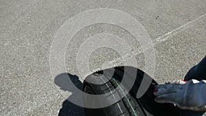 Man carries one tire, in area where there are a lot of sports racing cars