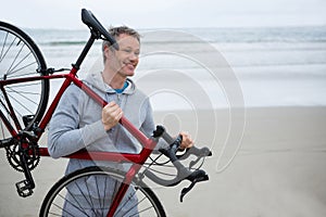 Man carrying bicycle on beach