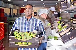 Man carrying box with pears at warehouse