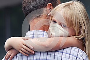 Man carrying child girl in medical face mask