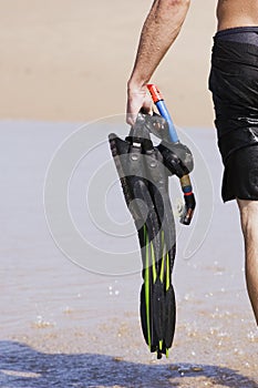 Man carrying diving gear on beach