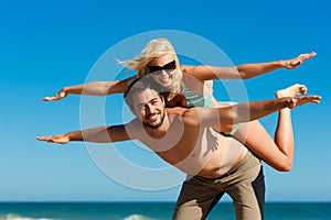 Man carrying his girl friend on the beach