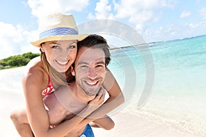 Man carrying his girlfriend on back on caribbean beach