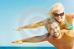 Man carrying his wife on beach in vacation