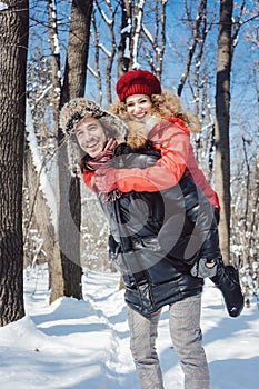 Man carrying his woman piggyback on a winter day