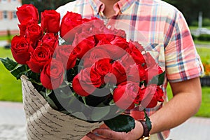 A man carrying a huge bouquet of red roses