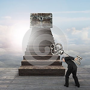 Man carrying key toward treasure chest on wood stairs