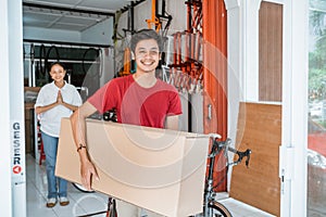 man carrying a large box of unassembled bicycles while buying a new bicycle