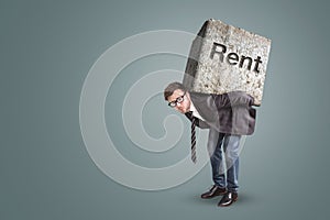 Man carrying a large stone engraved with the word `Rent`