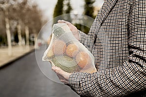 Man carrying a mesh bag full of fruit and vegs