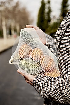 Man carrying a mesh bag full of fruit and vegs