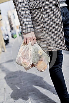 Man carrying a mesh bag full of fruit and vegs