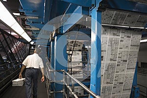 Man Carrying Newspaper Stack In Factory