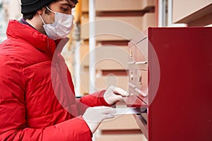 Man carrying packages while delivering mail in mailbox