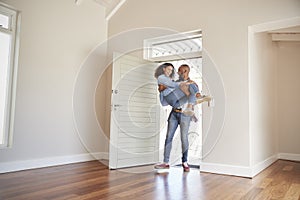 Man Carrying Woman Over Threshold Of Doorway In New Home