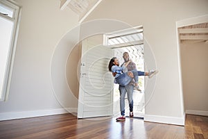 Man Carrying Woman Over Threshold Of Doorway In New Home