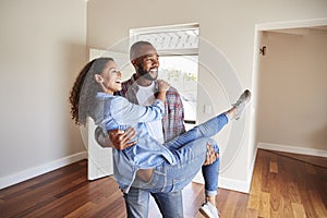 Man Carrying Woman Over Threshold Of Doorway In New Home