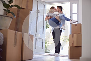 Man Carrying Woman Over Threshold Of New Home As Couple Move In Together