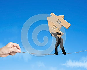 Man carrying wooden house and balancing on tightrope