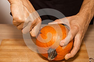 A man carves eyes and a mouth in a pumpkin for Halloween