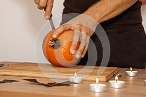 A man carves eyes and a mouth in a pumpkin for Halloween.