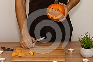 A man carves eyes and a mouth in a pumpkin for Halloween.