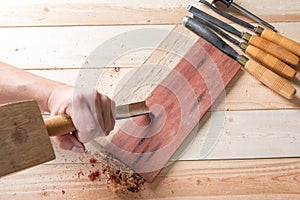 Man carving wood with handtools