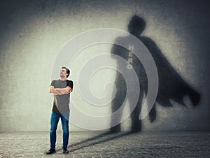 Man casting a superhero with cape shadow on the wall