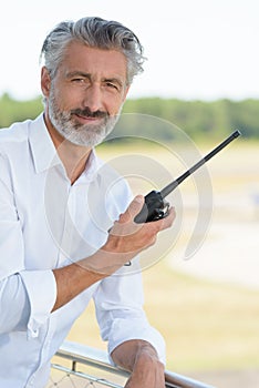 Man in casual attire holding walkie talkie