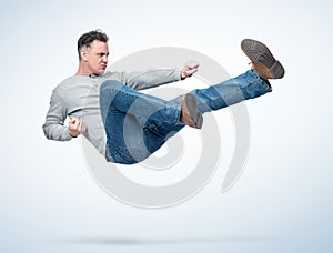 Man in casual clothes make karate fight jump, on light background