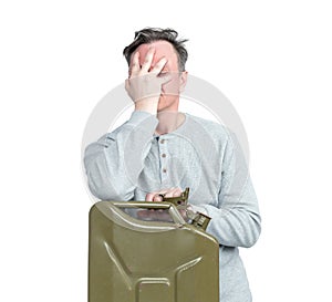 A man in casual clothes makes a facepalm leaning on an old gasoline canister, isolated on a white background.