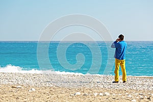 Man in casual Clothing talking on Phone at Sea Beach